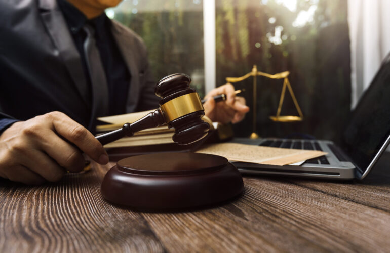Justice and law concept.Male judge in a courtroom with the gavel Justice and law concept.Male judge in a courtroom with the gavel, working with, computer and docking keyboard, eyeglasses, on table in morning light